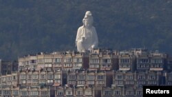 A 76-meter-high (249-feet) bronze-forged white Buddhist Avalokitesvara or Guan Yin statue, part of the Tsz Shan Monastery, stands behind luxurious houses at Taipo district in Hong Kong April 16, 2015. 