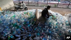 Seorang pekerja India memilah botol-botol plastik bekas sebelum dikirim untuk didaur ulang, di sebuah stasiun kereta pada Hari Lingkungan Dunia, Ahmadabad, India, 5 Juni2018.
