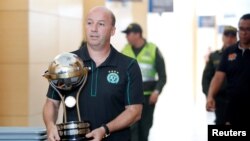 Marcelo Zolet, asesor legal del club brasileño de fútbol Chapecoense lleva una réplica del trofeo de la Conmebol tras recibirlo de los directores del club colombiano Santa Fé, el último campeón de la Copa Sudamericana en Medellín, Colombia.