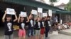 FILE - Protesters hold signs about the mass fish deaths in Nghe An Province, central Vietnam. Protests Sunday led to dozens of people being detained by police in Hanoi and Ho Chi Minh City.