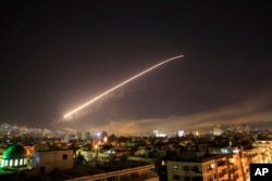 FILE - The Damascus sky lights up as the U.S., France and Britain launch an attack on three Syrian government facilities, April 14, 2018.