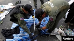 Thai policemen check the scene following an explosion near a camp of anti-government protesters at the Victory monument in central Bangkok, Jan. 19, 2014. 