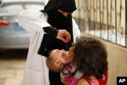FILE - A Yemeni health worker gives the polio vaccine to a child during a house-to-house polio immunization campaign in Sana'a, Yemen, Aug. 12, 2014.