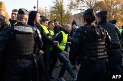 French gendarmes face "Yellow Vest" protesters demonstrating on the Champs-Elysees, in Paris, France, Nov. 17, 2018,