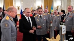FILE - Russian President Vladimir Putin, second left, and Defense Minister Sergei Shoigu, center, toast with champagne during an awards ceremony for troops who fought in Syria, in the Kremlin, in Moscow, Dec. 28, 2017. Putin says Russia's action in Syria has demonstrated the power of the nation's modernized military to the world. 
