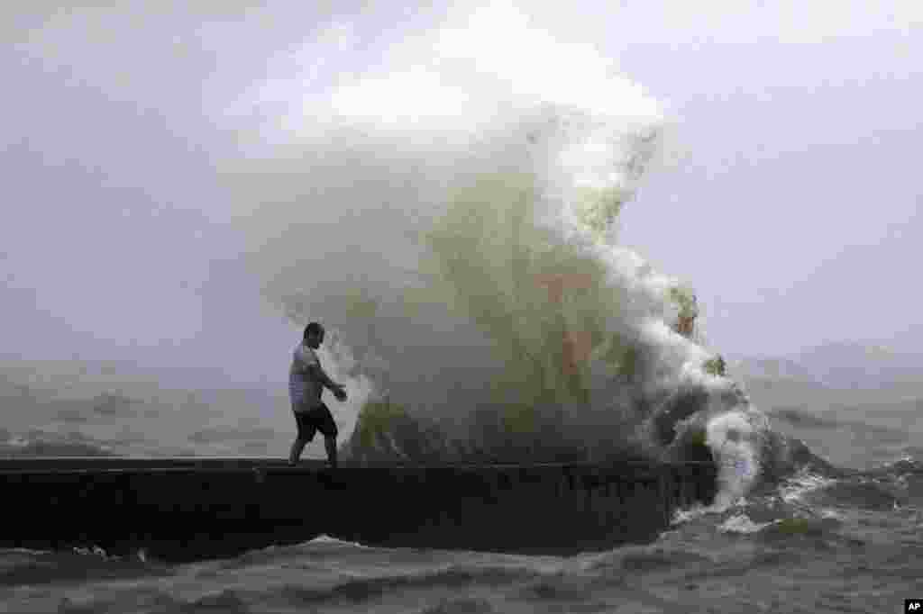 A wave crashes as a man stands on a jetty near Orleans Harbor in Lake Pontchartrain in New Orleans, June 7, 2020, as Tropical Storm Cristobal approaches the Louisiana Coast.