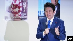 FILE - Japanese Prime Minister Shinzo Abe delivers remarks to families of Japanese citizens abducted by North Korea, in front of abduction awareness posters during an event in Tokyo, April 22, 2018.