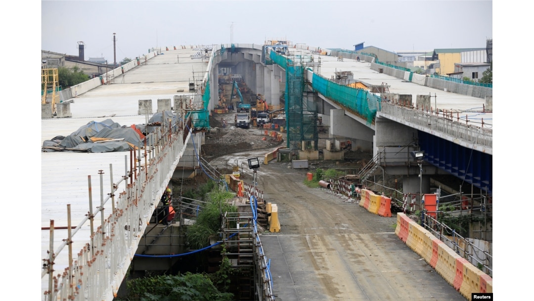 FILE - Workers walk over the newly dried concrete and secure linking steel bars of the 5.58 kilometer elevated highway in Caloocan City, metro Manila, Philippines, Aug. 2, 2017.