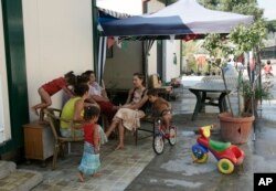 FILE - Women sit and talk while children play at a Gypsy camp in Rome, Aug. 6, 2008.