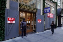 A security guard stands outside the heavily boarded Shreve & Co. jewelry store in San Francisco, Dec. 2, 2021.