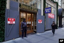 A security guard stands outside the heavily boarded Shreve & Co. jewelry store in San Francisco, Dec. 2, 2021.