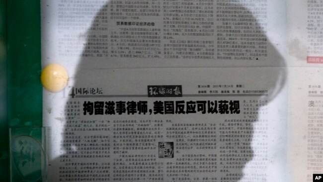 资料照片:一名女子在北京的某处报纸橱窗阅读《环球时报》。该报的文章呼吁忽视美国对中国打压维权律师的批评。(2015年7月14日)