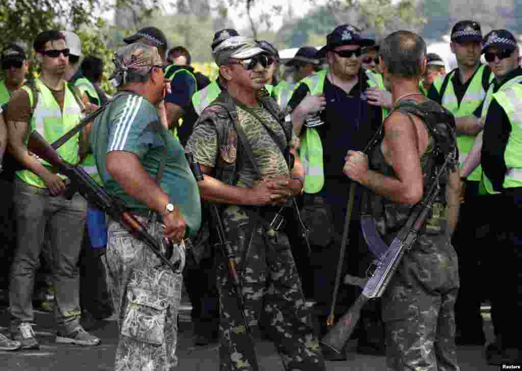 Pro-Russian separatists stand near Dutch and Australian forensic experts preparing to continue recovery work near the village of Rozsypne, in the Donetsk region, Aug. 4, 2014.