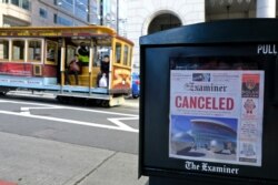 A newspaper headline announcing the closure of large events is displayed as a cable car goes down California Street, March 13, 2020, in San Francisco.