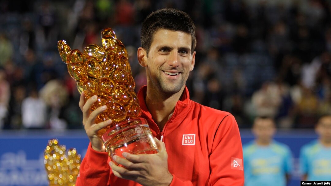 Novak Djokovic dari Serbia memegang piala setelah mengalahkan David Ferrer dari Spanyol dalam final Mubadala World Tennis Championship di Abu Dhabi, Uni Emirat Arab (28/12). (AP/Kamran Jebreili)