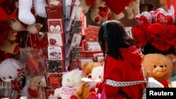 Una mujer camina junto al puesto de un vendedor ambulante que vende peluches y rosas antes del Día de San Valentín en San Gwann, Malta, el 13 de febrero de 2025. 