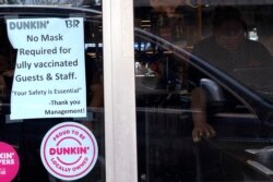 FILE - A COVID advisory is displayed at a Dunkin' store in Arlington Heights, Illinois, June 30, 2021.