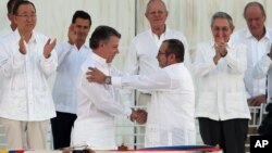 Presiden Kolombia Juan Manuel Santos (depan kiri) berjabat tangan dengan Komandan tertinggi FARC, Rodrigo Londono, setelah penandatangan kesepakatan perdamaian di Havana, Kuba, 26 September lalu. Pemilih Kolombia hari Minggu (2/10) menolak kesepakatan damai ini.