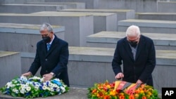 Presiden Jerman Frank-Walter Steinmeier (kanan) dan Ketua Parlemen Israel Mickey Levy menaruh rangkaian bunga di Monumen Peringatan Holocaust di Berlin, sebagai bagian dari peringatan Hari Holocaust Internasional pada 27 Januari 2022. (Foto: Pool Photo via AP/John MacDougall)