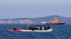 FILE - Migrants on a dinghy are approached by a Greek coast guard boat near the port of Thermi, as they crossed part of the Aegean Sea from Turkey to the island of Lesbos, Greece, March 1, 2020. 