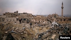 A member of forces loyal to Syria's President Bashar al-Assad stands with a civilian on the rubble of the Carlton Hotel, in the government controlled area of Aleppo, Syria, Dec. 17, 2016.