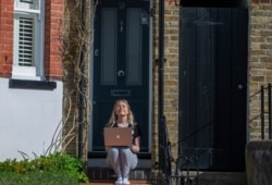 FILE - University student Piera Gerry is back home with her parents where she continues her studies online after schools closed due to the coronavirus outbreak, in Berkhamsted, England, April 5, 2020.