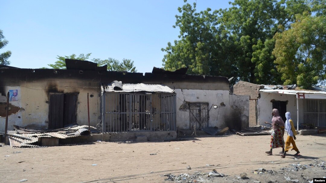 FILE - Women walk by homes destroyed by Boko Haram militants in Bama, Borno State, Nigeria.
