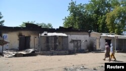 FILE - Women walk by homes destroyed by Boko Haram militants in Bama, Borno State, Nigeria.