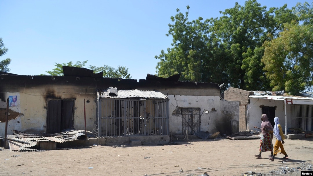 FILE - Women walk by homes destroyed by Boko Haram militants in Bama, Borno State, Nigeria.