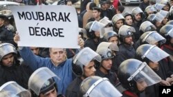 Xwenîşanderekî Misirî nivîseke bi Frensî bilind dike ku dibêje, "Mubarek, Derkeve"