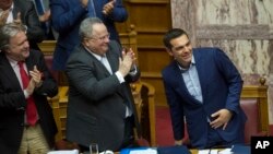 Greek Prime Minister Alexis Tsipras, right, is applauded by lawmakers after the end of his speech during a parliamentary session, in Athens, June 16, 2018. 