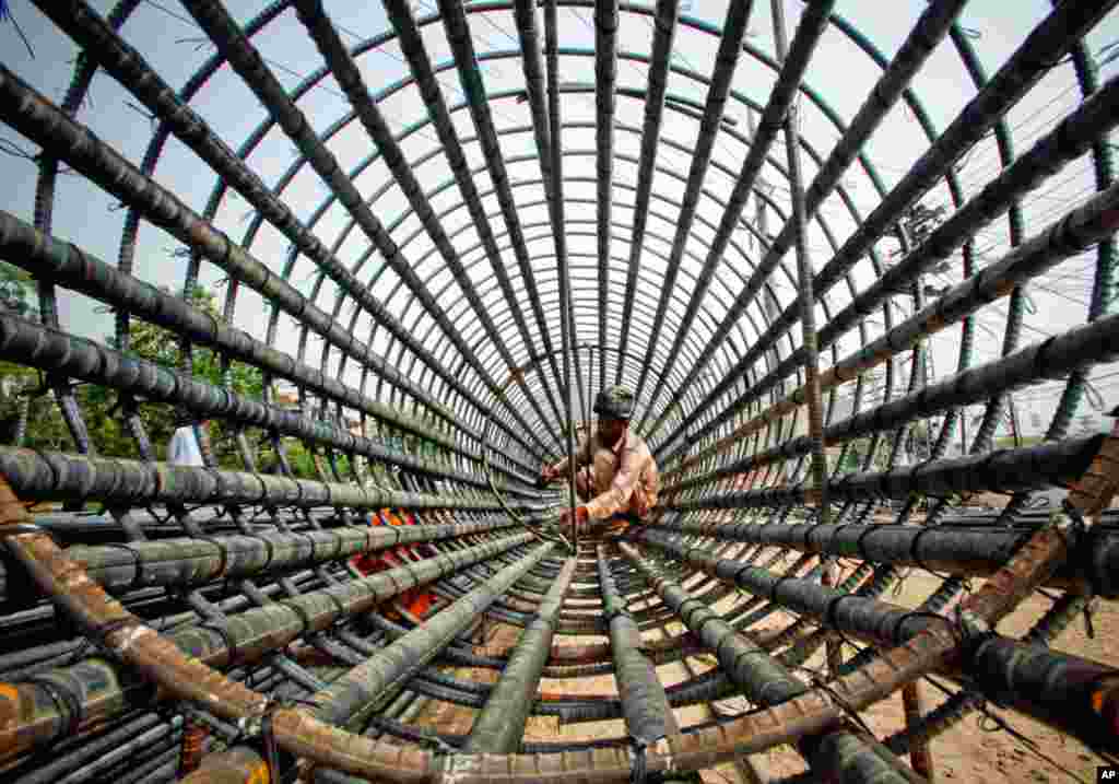 Masy 26: A labourer attaches iron rods to a column at the construction site of a flyover in Lahore. (Reuters)