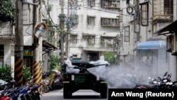 Sejumlah tentara mengenakan alat pelindung diri menyemprotkan cairan disinfektan dari sebuah kendaraan menyusul lonjakan kasus infeksi COVID-19 di distrik Tucheng, New Taipei City, Taiwan, 27 Mei 2021. (Foto: Ann Wang/Reuters)