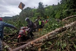 Sejumlah pengendara motor melewati jalan yang rusak akibat tanah longsor yang dipicu gempa dekat Mamuju, Sulawesi Barat, Sabtu, 16 Januari 2021.(Foto: AP)