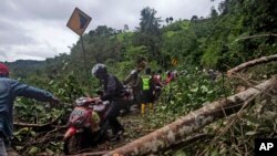 16일 인도네시아 술라웨시섬 마무주 인근 주민들이 지진 피해 현장을 지나고 있다. 
