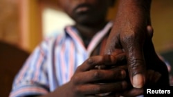 Nine-year-old Tumelo holds his grandmother's hand after taking his medication at Nkosi's Haven, south of Johannesburg November 28, 2014. Nkosi's Haven provides residential care for destitute HIV-positive mothers and their children, whether HIV-positive or