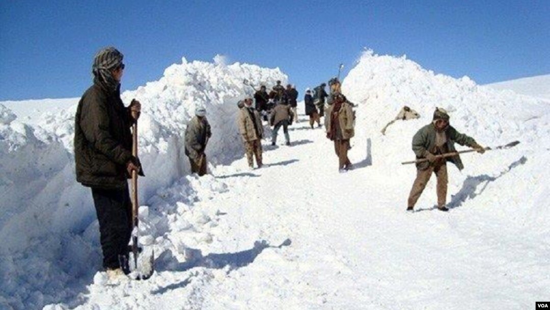 Des Afghans mettent en neige sur le côté d'une route pour déblayer le passage, en Afghanistan, le 5 février 2017. (VOA)
