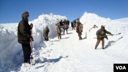 Des Afghans mettent en neige sur le côté d'une route pour déblayer le passage, en Afghanistan, le 5 février 2017. (VOA)