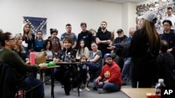 Caucusgoers listen as a supporter of Democratic presidential candidate Pete Buttigieg, right, speaks in support of him at Coronado High School in Henderson, Nevada, Feb. 22, 2020.