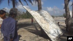 Thai people look at a large chunk of metal found on a beach in Nakhon Si Thammarat province, Thailand, Jan. 24, 2016. 