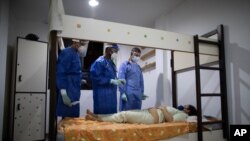Médicos venezolanos visitan a una paciente con COVID-19, en su habitación de la residencia de antiguos estudiantes que se utiliza para poner en cuarentena a enfermos asintomáticos, el sábado 29 de agosto de 2020. 