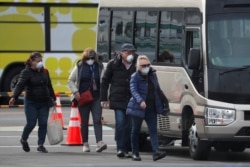 Russian passengers walk with their luggage after leaving the coronavirus-hit Diamond Princess cruise ship docked at Yokohama Port, south of Tokyo, Feb. 20, 2020.