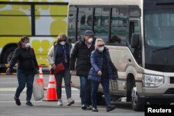 Russian passengers walk with their luggage after leaving the coronavirus-hit Diamond Princess cruise ship docked at Yokohama Port, south of Tokyo, Feb. 20, 2020.