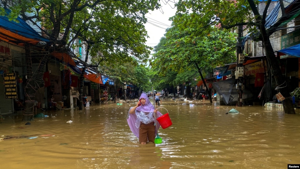 Một người dân lội trên đường phố ngập nước ở thành phố Thái Nguyên sau bão Yagi 