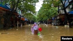 Vietnam'ın Thai Nguyen kentinde bir kadın sular altında kalan bir caddede yürüyor. 