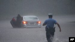A Philadelphia police officer rushes to help a stranded motorist during Tropical Storm Isaias, Aug. 4, 2020, in Philadelphia.