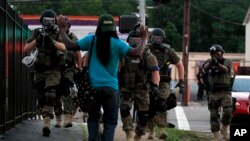 Policías antimotines obligan a un manifestante a mantener sus brazos en alto en Ferguson, Misuri.