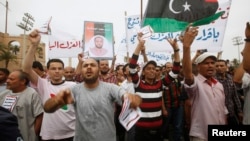 Protesters wave a Libyan flag as they demonstrate in Martyrs' Square demanding Gadhafi-era officials to be banned from taking up political posts, in Tripoli, Libya, May 5, 2013.