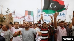 Protesters wave a Libyan flag as they demonstrate in Martyrs' Square demanding that Gadhafi-era officials be banned from taking up political posts, in Tripoli, Libya, May 5, 2013.