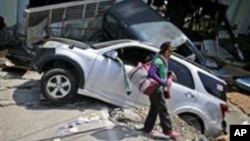 Una mujer pasa cerca de los restos de automóviles arrasados por el terremoto del viernes 28 en el vecindario de Balaroa en Palu, Sulawesi Central, Indonesia, el martes 2 de octubre de 2018.